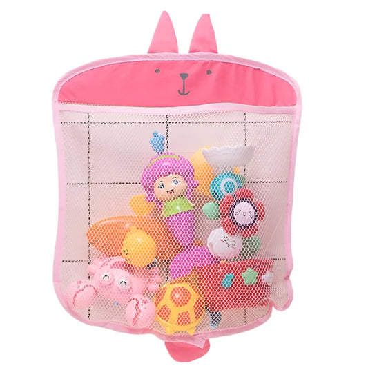 Pink mesh toy storage bag with suction cups holding bath toys on a tiled bathroom wall.